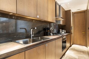 A modern kitchen with wooden cabinets, stainless steel appliances, and a marble countertop.