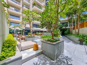 A modern outdoor courtyard with seating areas, planters, and a central tree.