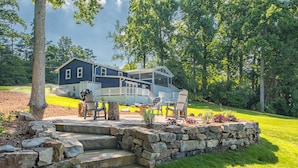 A two-story house with a porch, stone steps, and outdoor seating.