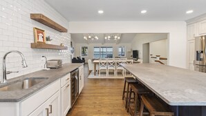 A modern kitchen with white cabinets, a wooden countertop, and a large island with bar stools.