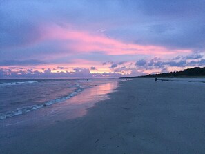 A beach with a calm sea and a sunset sky.