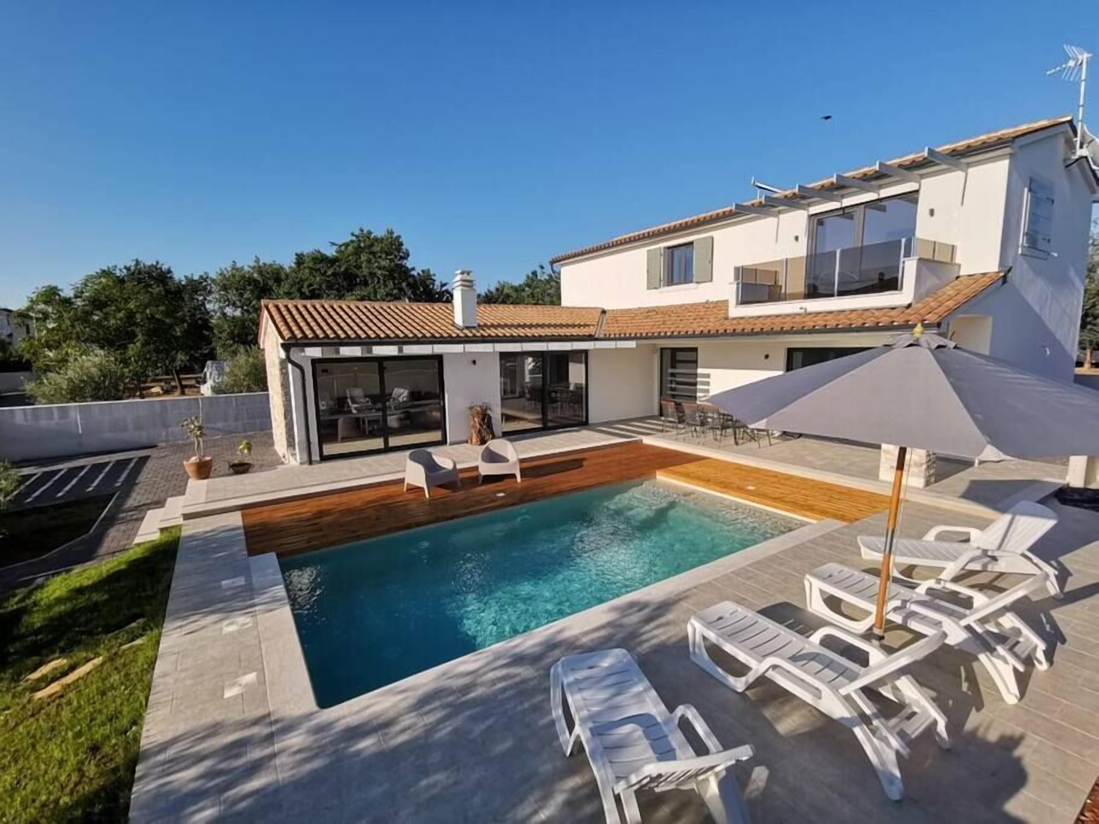 A modern house with a swimming pool, outdoor seating, and a covered patio area.