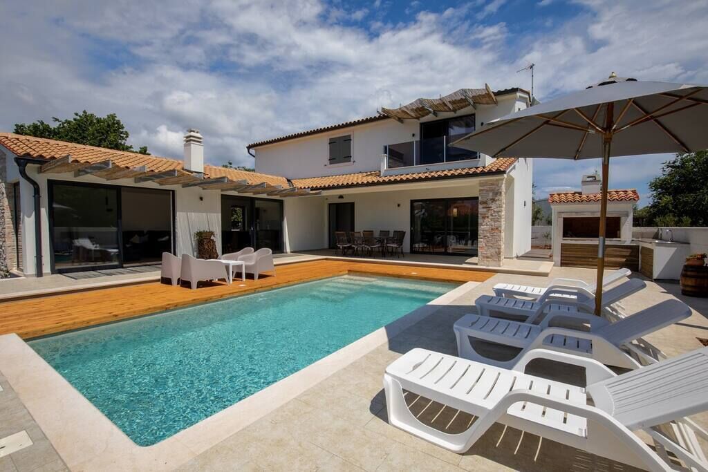Una casa moderna con piscina, mobiliario exterior y una zona de patio.
