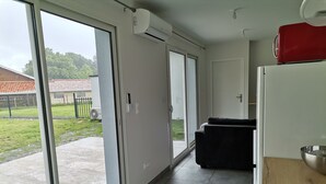 Eine moderne Küche mit einer Schiebeglasdoor zu einer Terrasse, einem schwarzen Sofa und einem roten Gerät auf der Arbeitsplatte.