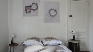Un dormitorio con una cama, dos almohadas, una mesita de noche, una lámpara y dos adornos en la pared.