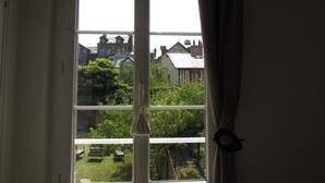 Una ventana con vistas a un jardín y casas al fondo.