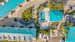 Luchtbeeld van een resort met meerdere zwembaden, loungegedeeltes en een aangelegde centrale zone.