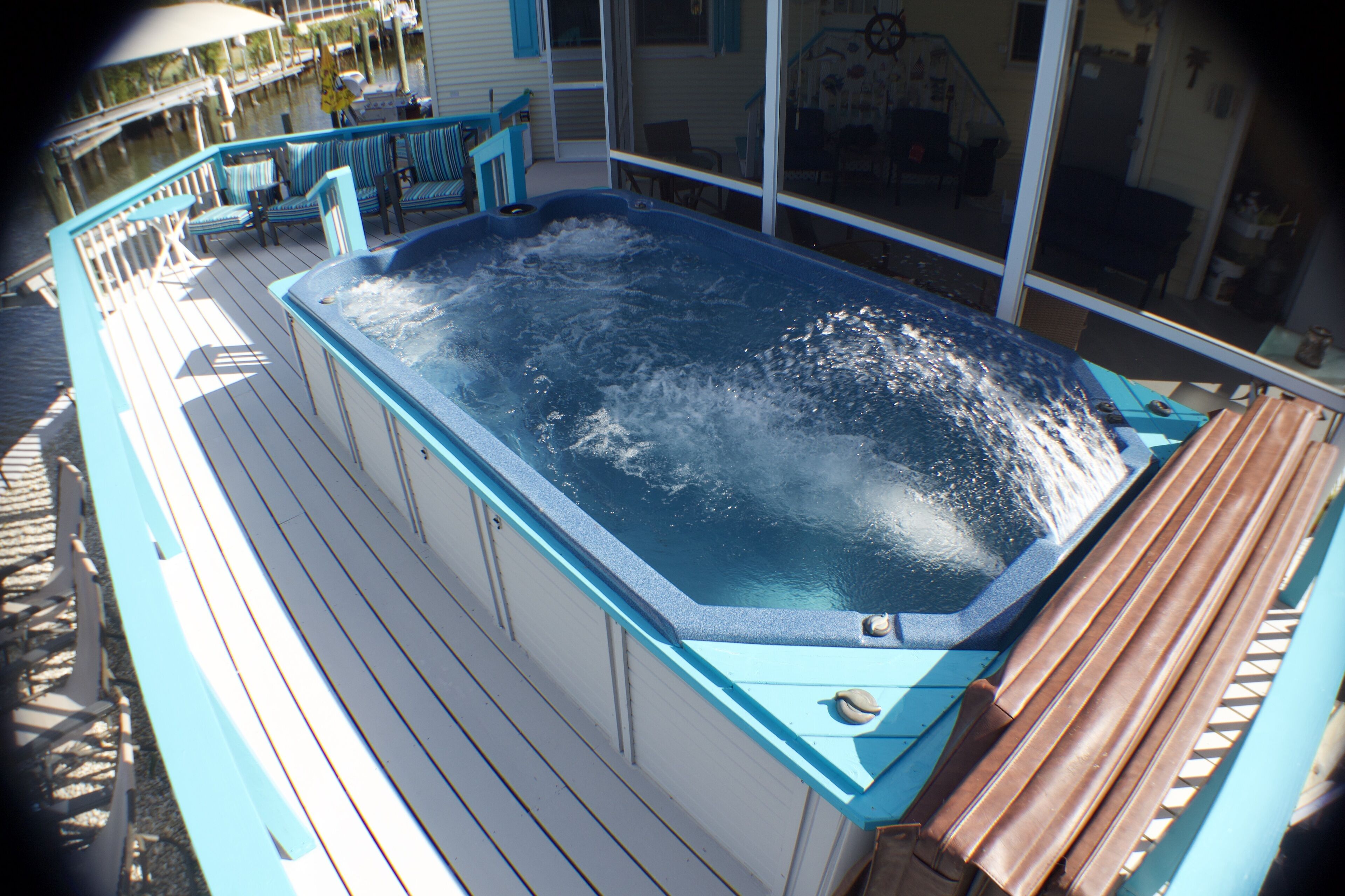 A hot tub on a wooden deck with chairs and a table.