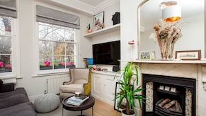 A living room with a fireplace, a sofa, a TV, and a potted plant.