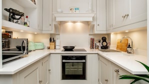 A modern kitchen with white cabinetry, a built-in oven, a microwave, and a sink.