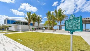 Un edificio moderno con facciata in vetro, una zona verdeggiante e un cartello che indica la spiaggia pubblica di St. Augustine.