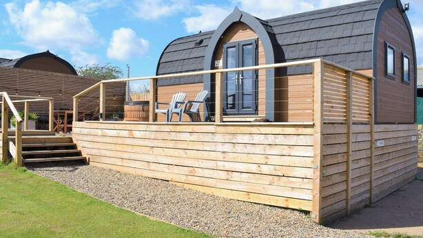 A wooden cabin with a deck, two windows, and a staircase leading to the entrance. - 1 bedroom accommodation in Tynely, near Embleton (Tynely, near Embleton)
