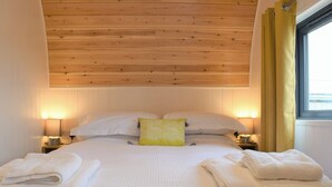 A neatly made bed with white linens and a yellow pillow, two bedside lamps, and a window with yellow curtains. - 1 bedroom accommodation in Tynely, near Embleton (Tynely, near Embleton)