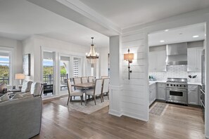 A modern kitchen with white cabinetry, a stainless steel stove, and a chandelier.