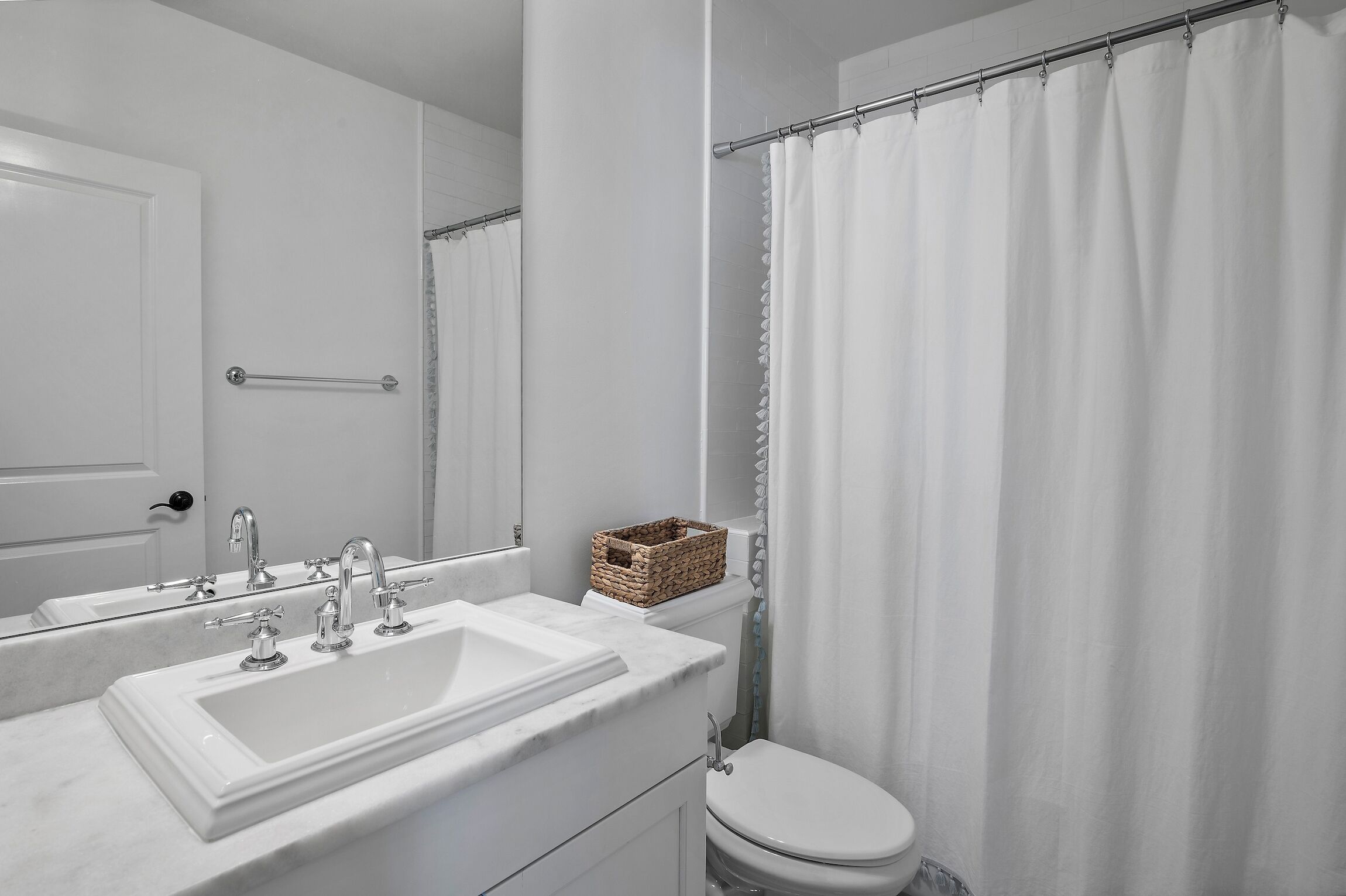 Une salle de bain avec un lavabo blanc, un miroir et des toilettes.