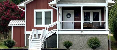 A two-story building with a porch, a staircase, and a door with a wreath.