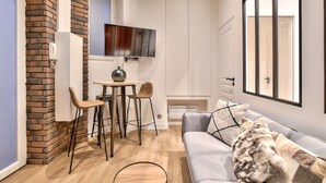 En kompakt opholdsstue med spiseplads, sofa og fjernsyn.
