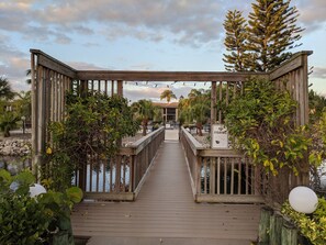 A wooden deck leading to a building with a 'NO FISHING' sign, surrounded by greenery and palm trees. - 1st floor Ft. Myers Davis Lake Condo, minutes to Sanibel and Fort Myers beach (Fort Myers)