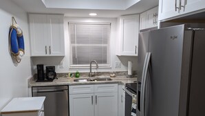A modern kitchen with white cabinets, a stainless steel refrigerator, and a built-in oven. - 1st floor Ft. Myers Davis Lake Condo, minutes to Sanibel and Fort Myers beach (Fort Myers)