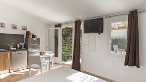 Une pièce compacte comprenant un coin cuisine, un espace repas et une grande fenêtre avec des rideaux.