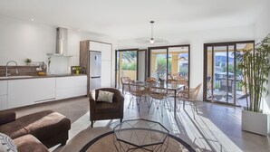 Une cuisine moderne dotée d’un four encastré et d’un coin repas avec une table en verre et des chaises en osier.