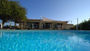 Une piscine avec des chaises longues et un bâtiment en arrière-plan.