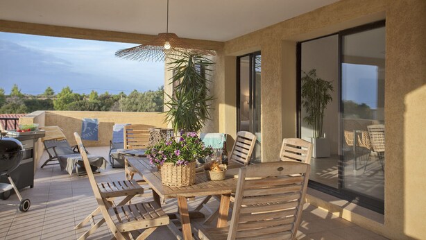 Une terrasse en bois avec une table, des chaises et un luminaire suspendu.
