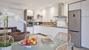 Une cuisine moderne avec des meubles blancs, des appareils en acier inoxydable et une table à manger en verre.