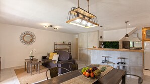 A modern living room with a dining area, a kitchen with a bar, and a staircase. - location de vacances figuier avec jardin barbecue piscine chauffée à Calvi (Calvi)