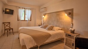 Ein Schlafzimmer mit einem Bett, einem Sessel, einem Fernseher und einem Nachttisch mit einer Lampe.