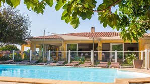 A pool area with lounge chairs and a building with a tiled roof.
