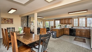 A spacious kitchen with wooden cabinets, a dining area with a wooden table and chairs, and a stone wall. - Get away from it all (Foristell)