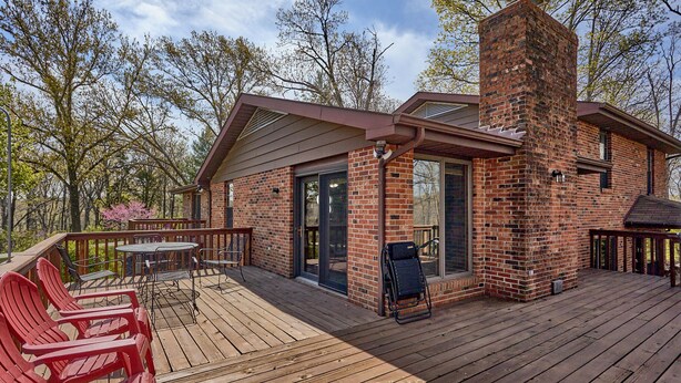 A wooden deck with outdoor seating and a brick chimney. - Get away from it all (Foristell)