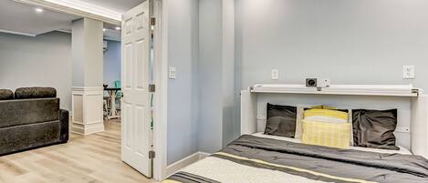 Un dormitorio con cama, mesita de noche y puerta que da a otra habitación.