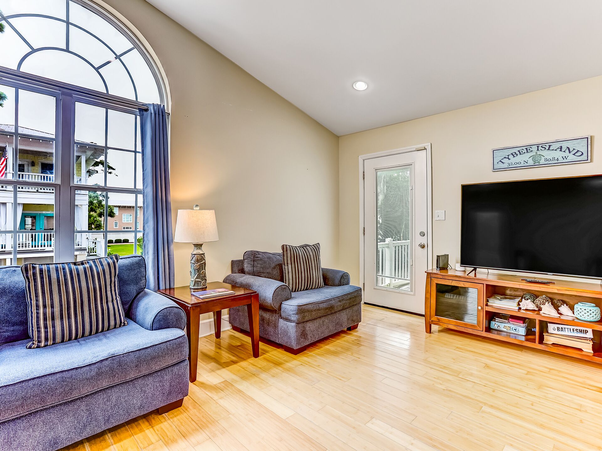 A modern living room with a large window, a flat-screen TV, and a wooden entertainment unit.
