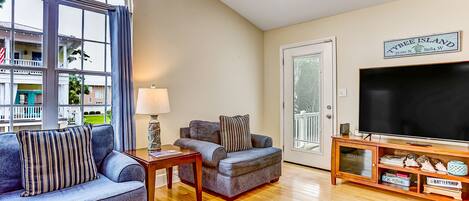 A modern living room with a large window, a flat-screen TV, and a wooden entertainment unit.