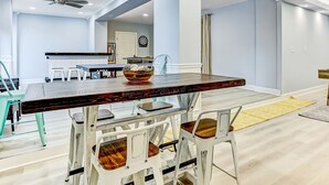 A dining area with a wooden table, white chairs, and a ceiling fan. - Heated Pool Access, Ping Pong & Foosball! (Tybee Island)