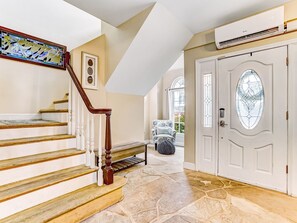 A staircase with wooden steps and white balusters, leading to a room with a stone floor and a white door with a glass panel. - Heated Pool Access, Ping Pong & Foosball! (Tybee Island)