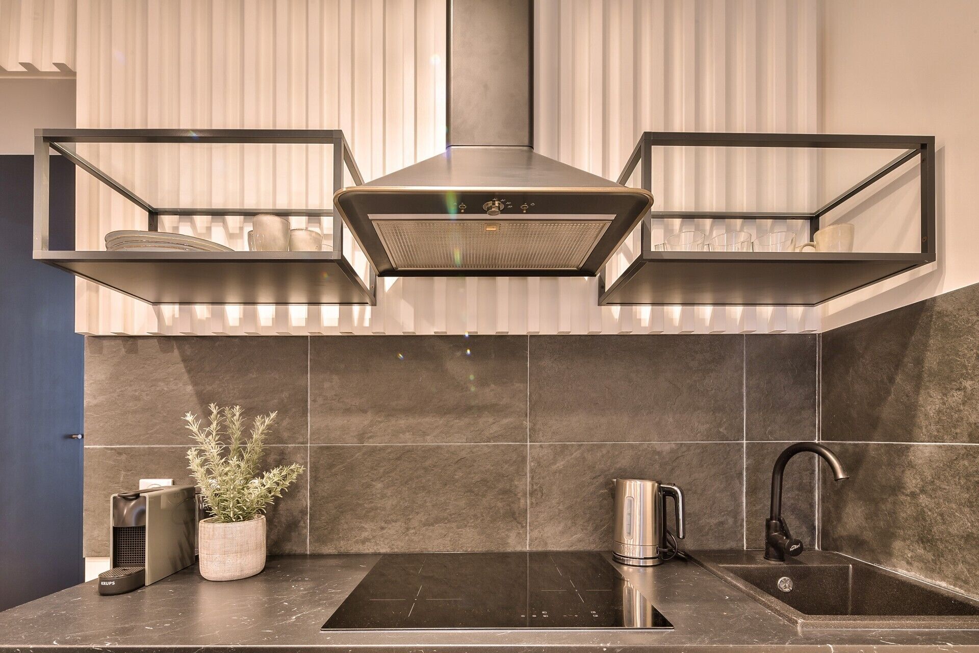 Een moderne keuken met een roestvrijstalen afzuigkap, een inbouwspoelbak en een waterkoker.