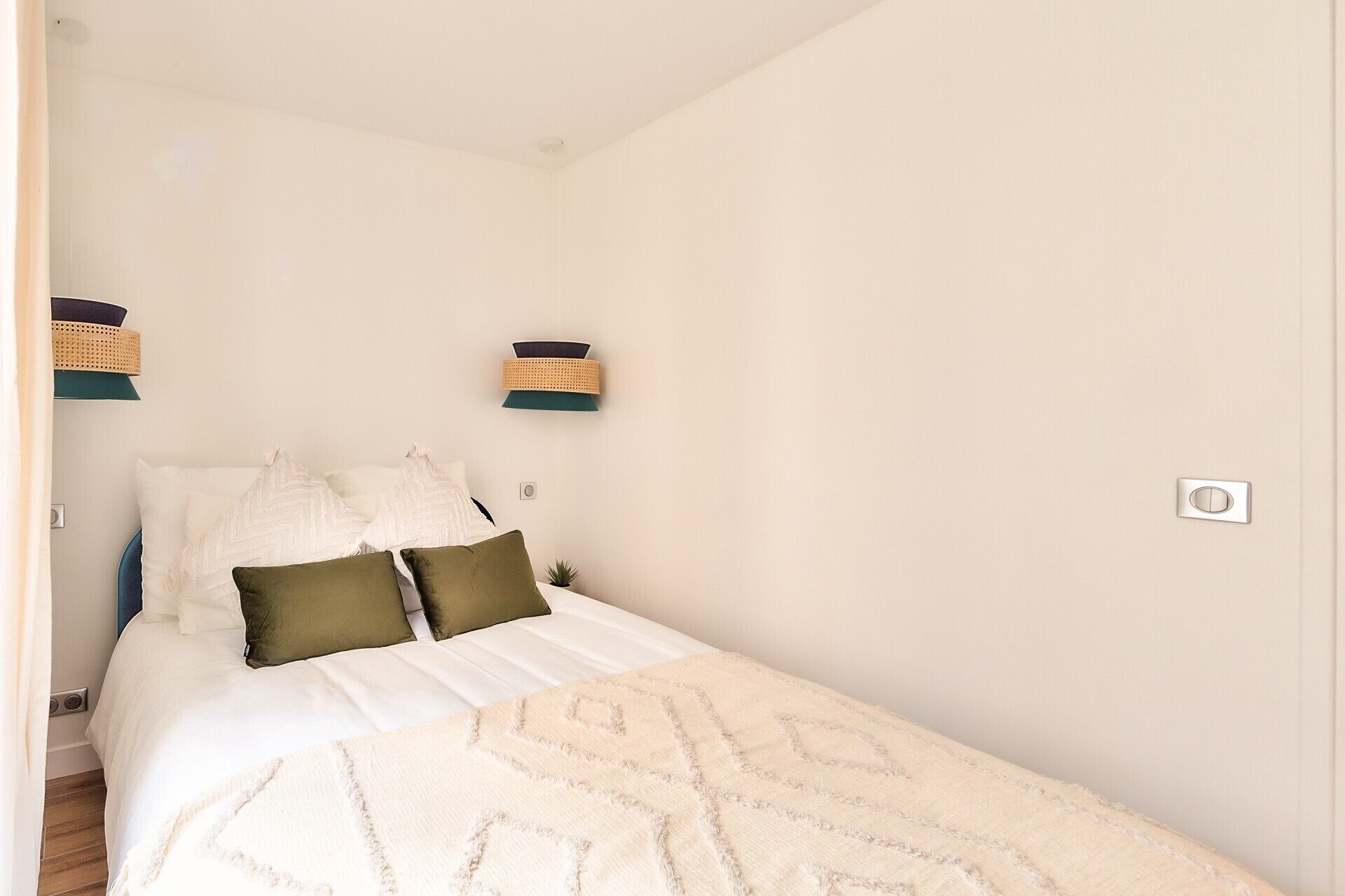 Un dormitorio con cama, almohadas, un estante en la pared y un interruptor de luz.