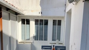 A small outdoor dining area with a table set for two, two chairs, and a bottle of wine. - Maison sur ÎLE DE RÉ (Ars-en-Ré)
