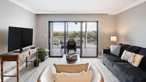 Un salon moderne doté d’un téléviseur à écran plat, d’un canapé, d’une table basse et d’un balcon offrant une vue agréable.