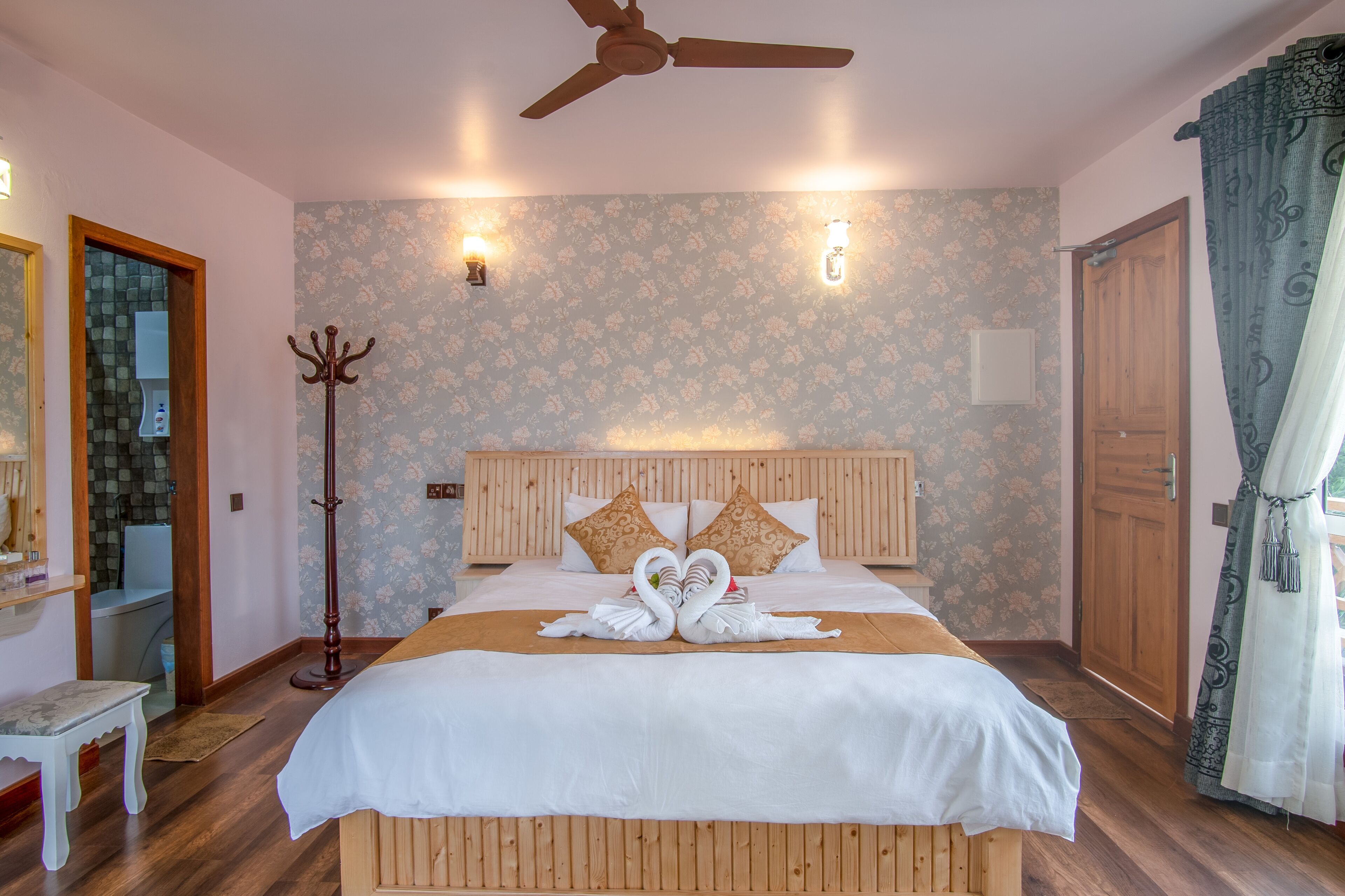 Un dormitorio ordenado con una cama de madera, un ventilador de techo y un papel tapiz floral.