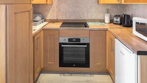 A kitchen with wooden cabinets, a built-in oven, a microwave, and a toaster. - 2 bedroom accommodation in Hunstanton (Hunstanton)