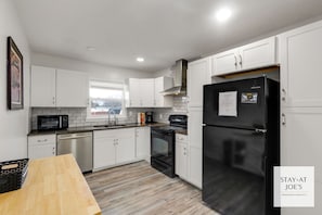 A modern kitchen with white cabinets, a black refrigerator, a microwave, and a stove. - Private 4 BDRM house, 5 Miles from Downtown #6 (Indianapolis)
