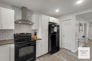 A modern kitchen with white cabinets, a black stove, and a black refrigerator. - Private 4 BDRM house, 5 Miles from Downtown #6 (Indianapolis)
