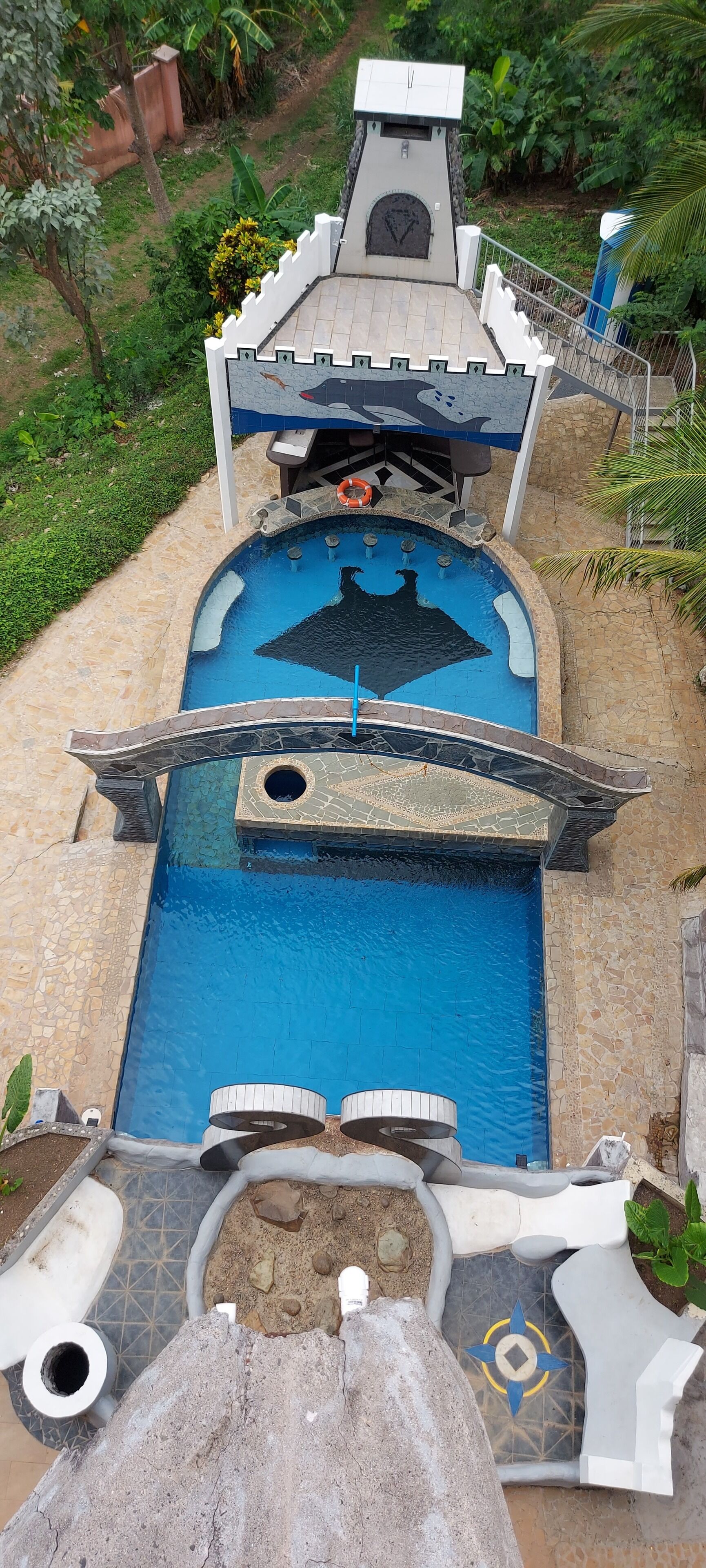 A swimming pool with a unique design, including a bridge and a decorative wall.