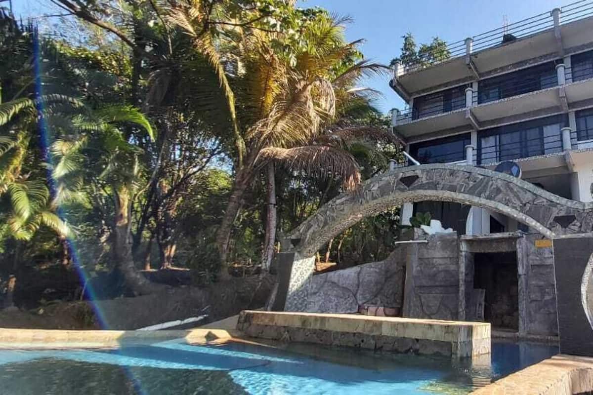 A modern hotel with a pool area featuring a stone archway and a large rock formation.