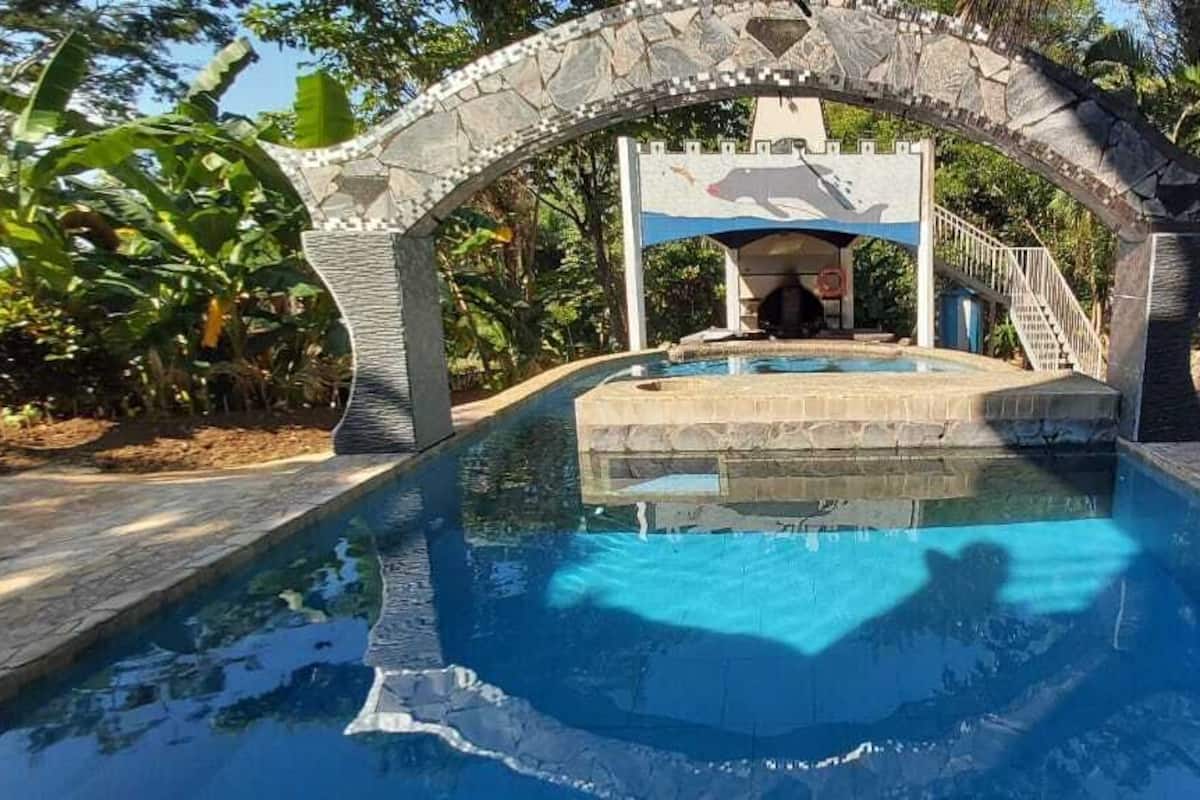 A swimming pool with a stone archway and a lifeguard stand.