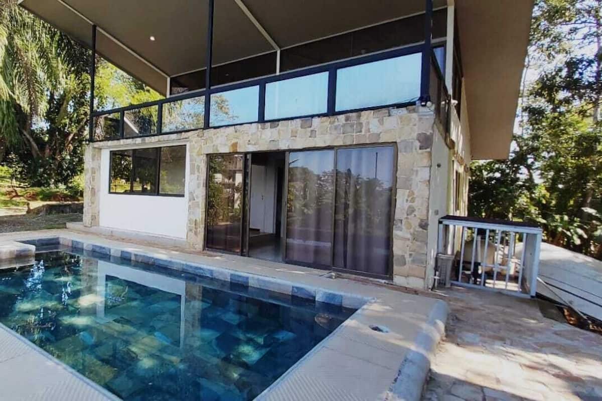 A modern house with a swimming pool, stone walls, and large windows.